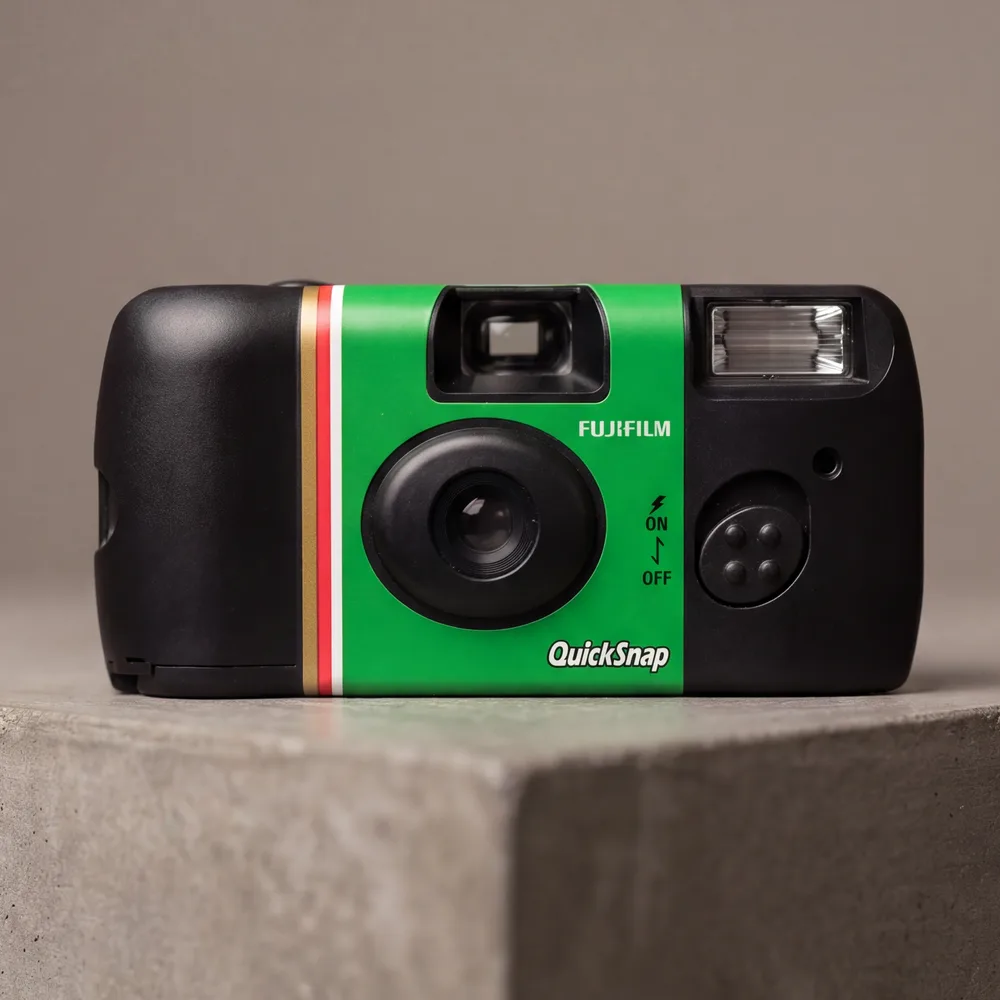 The same camera rendered from its own reference photographs, on concrete in directional light. The FUJIFILM and QuickSnap lettering is exactly as printed.