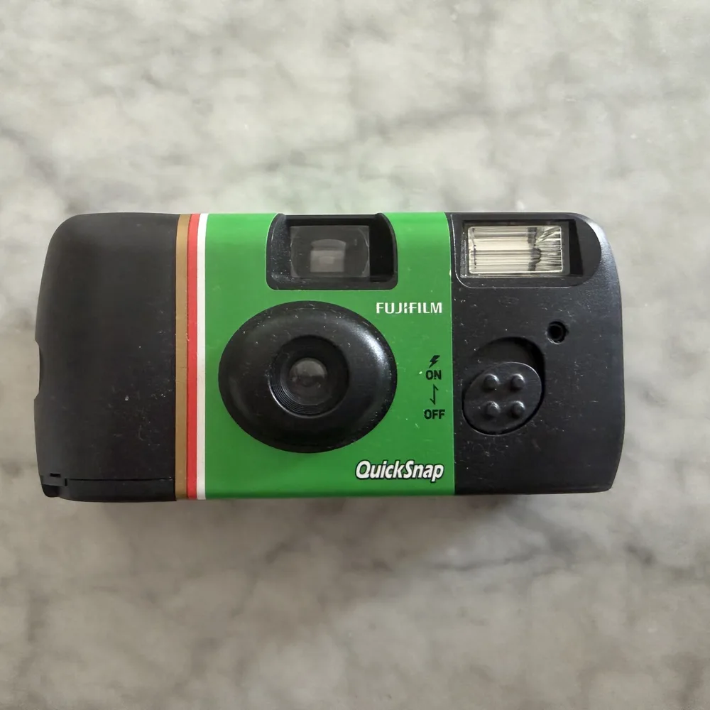 A plain reference photograph of a Fujifilm QuickSnap disposable camera on a kitchen counter, evenly lit and unstyled.